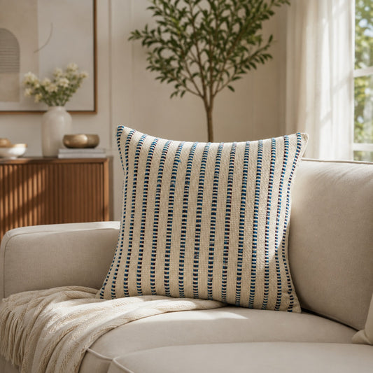 Blue and white striped decorative cushion styled on a neutral armchair