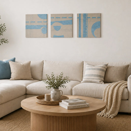 Set of three blue and cream abstract wall art panels with geometric shapes above a neutral sofa