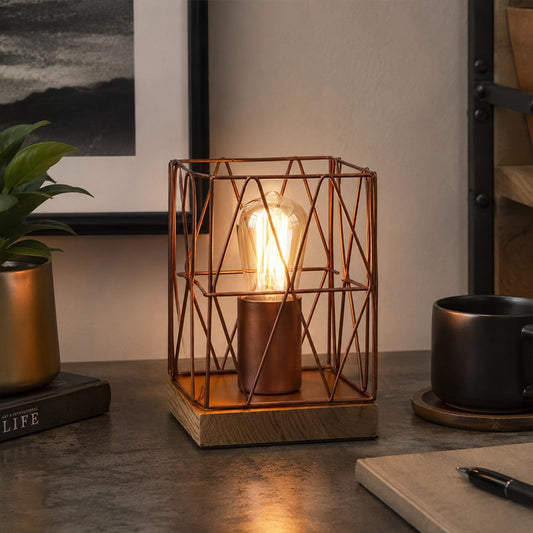 Brown metal table lamp with wire frame and exposed bulb on desk