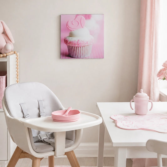 Pink cupcake glass wall art displayed in a pastel dining area with a white table and high chair