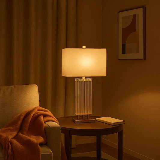 Glass table lamp with cream shade on side table beside armchair in warm living room