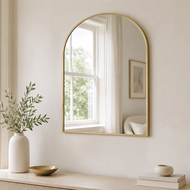 Gold arched wall mirror above bathroom sink with neutral decor