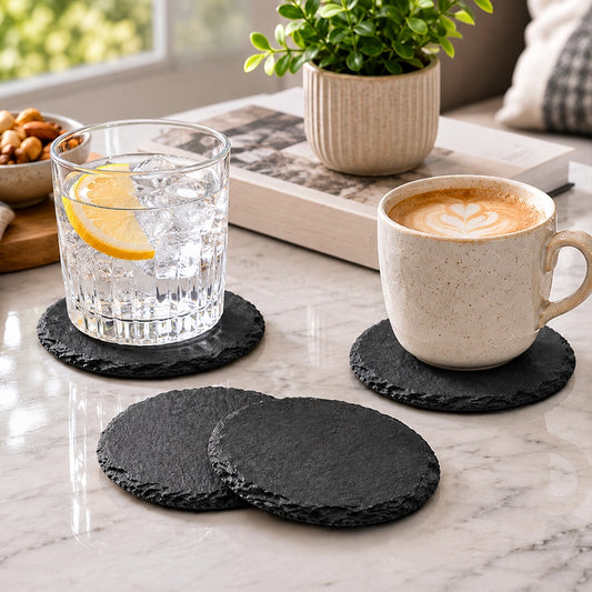 Set of four grey round textured coasters displayed with drinks on a marble coffee table