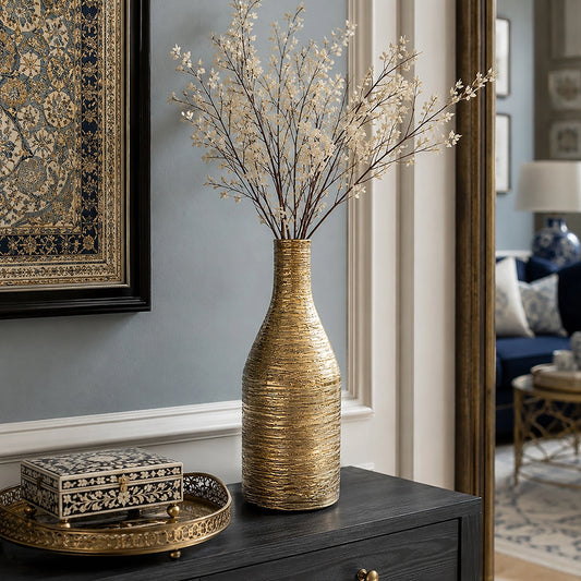 Large gold textured ceramic vase with delicate decorative branches displayed on a dark console table