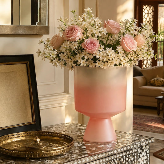Large matte pink glass vase with pedestal base filled with soft pink and white flowers