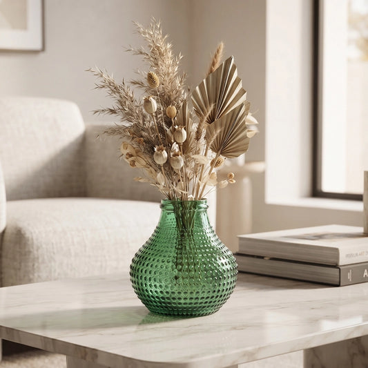 Small green textured glass vase with dried botanical stems styled on a marble coffee table
