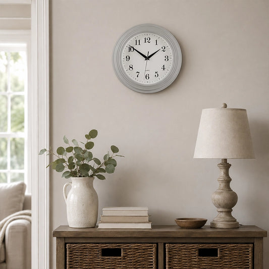 Vintage grey round wall clock above side table with lamp and vase