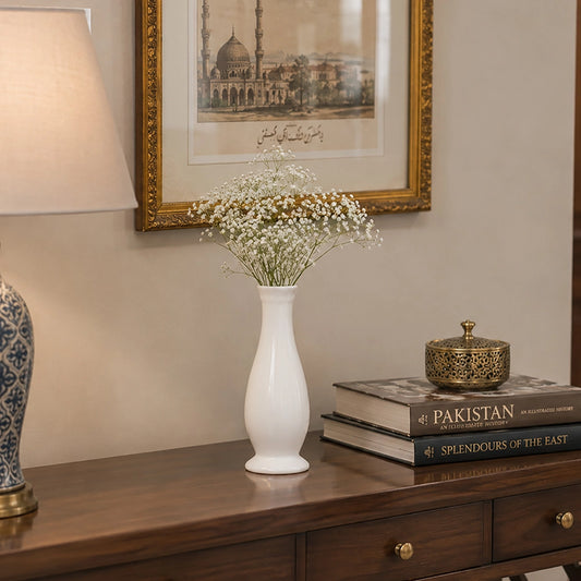 White curved ceramic vase with delicate white flowers styled on a wooden console table