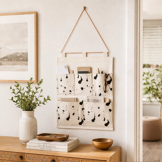 White fabric hanging wall organiser with black splatter pattern and multiple storage pockets