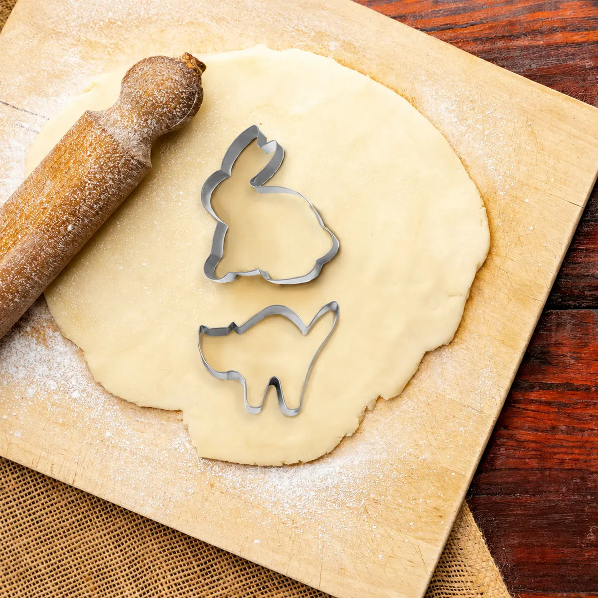 6 piece animal shape cookie cutter set including rabbit and cat on rolled dough with a rolling pin
