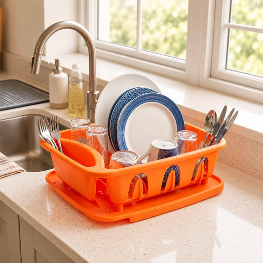 Orange plastic dish drainer holding plates, cups and cutlery on a kitchen counter next to the sink
