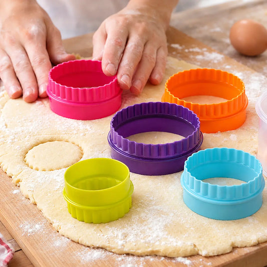 Set of 5 round fluted cookie cutters in bright colors cutting circles from rolled dough