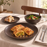 Dark brown 12-piece stoneware dinner set with dinner plate, side plate and salad bowl on a beige tablecloth