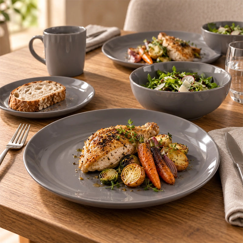 Grey 12-piece stoneware dinner set with plate, side plate, bowl and mug served with roast chicken and vegetables on a wooden table