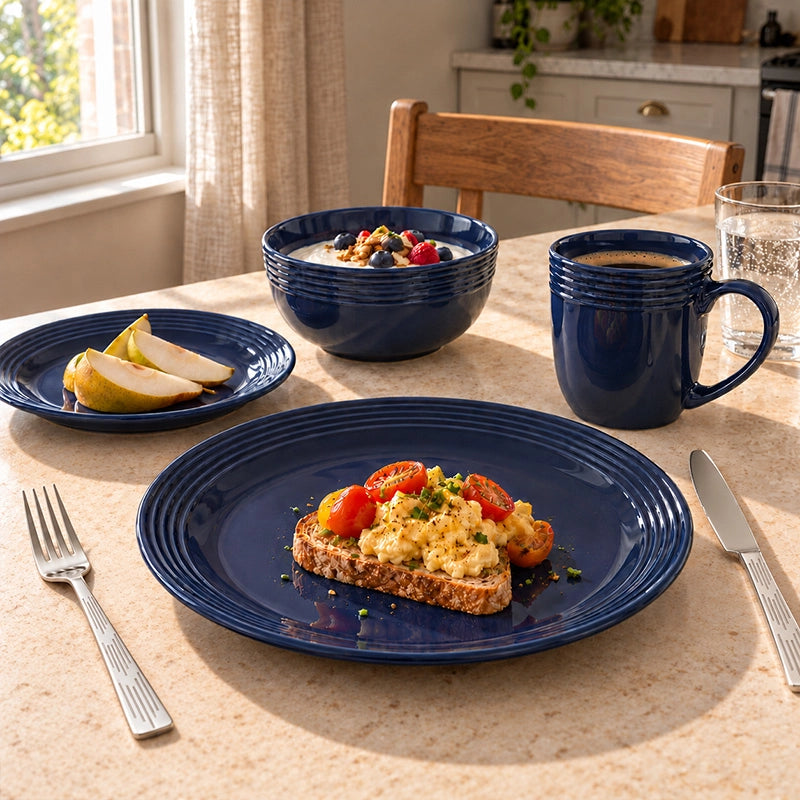 Dark blue grooved stoneware dinner set with dinner plate, side plate, bowl and mug on a wooden table with a breakfast toast
