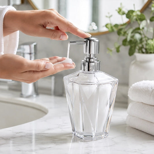 Clear acrylic lotion dispenser with pump being used beside a bathroom sink