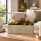 Artificial succulents in a rectangular grey cement pot displayed on a wooden indoor surface