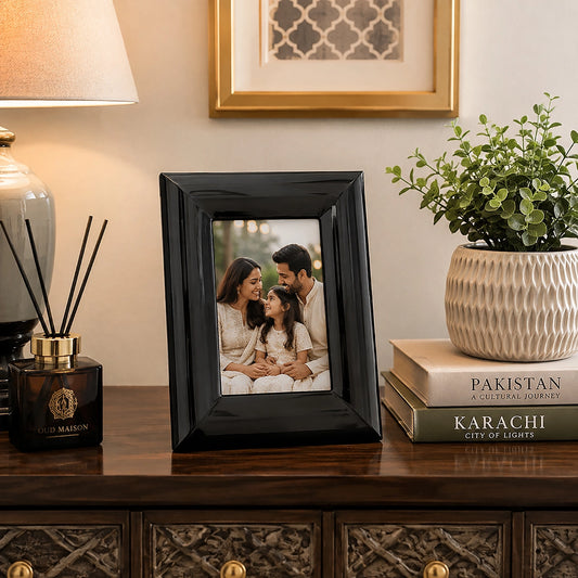 Black 4x6 photo frame with family picture on wooden sideboard