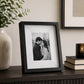 Black box photo frame displaying a family photograph on table