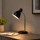 Black desk lamp on study table with notebook and soft warm light