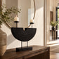Black sculptural double candle holder with two lit candles displayed on a wooden console table