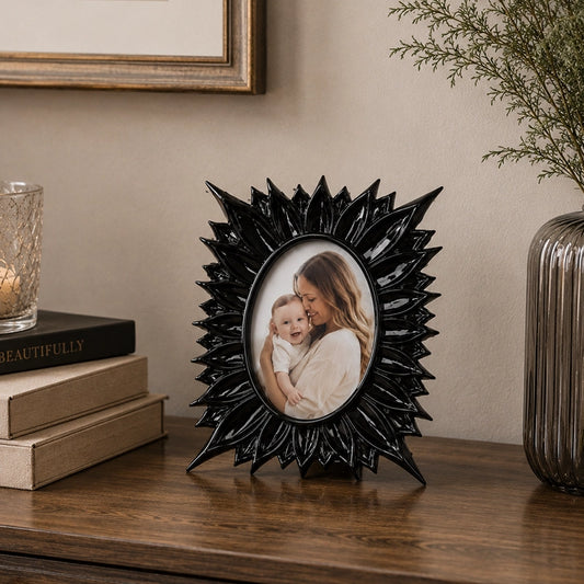 Black floral photo frame with decorative textured border on wooden surface