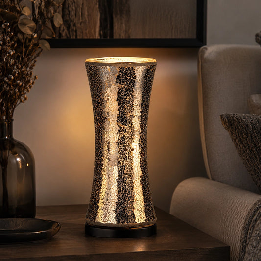 Black glass table lamp with warm glow on side table beside sofa