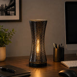 Black glass table lamp with warm glow on office desk