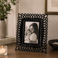 Black photo frame with textured border displaying portrait photograph