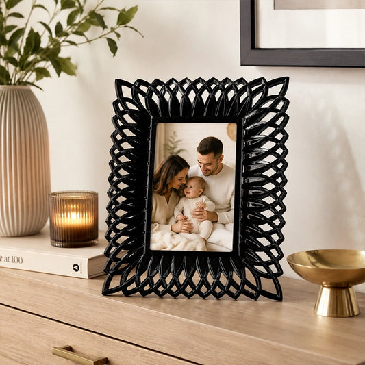 Black decorative photo frame with woven pattern border on tabletop
