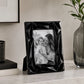 Black plastic picture frame with modern design on marble surface