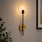 Black and gold ring wall light with exposed bulb on living room wall