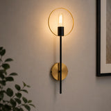 Black and gold ring wall light with exposed bulb on living room wall