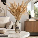 Black and white patterned ceramic vase with tall dried pampas grass in a modern living room