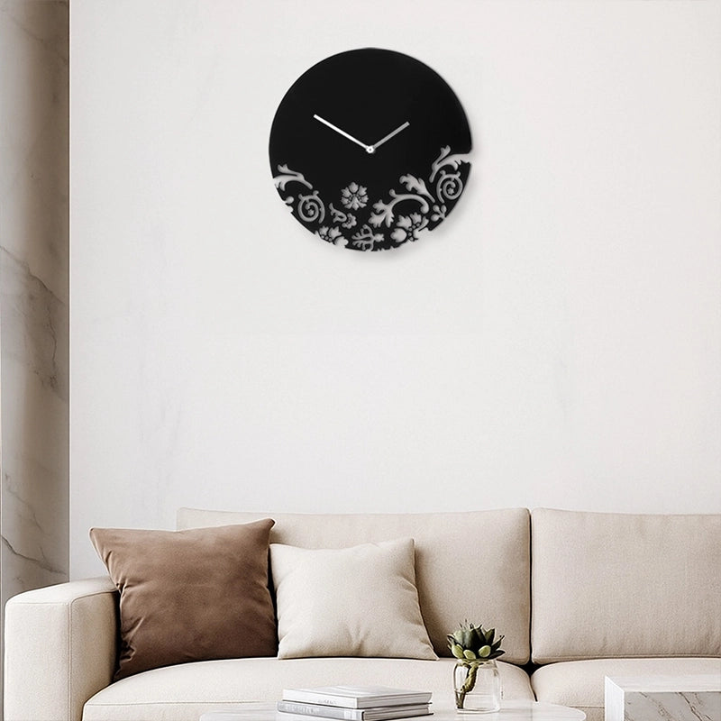 Black wall clock with white floral pattern above sofa in living room