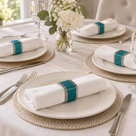 Blue glitter napkin rings holding white napkins with teal gem accents on a formal table