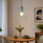 Blue wireframe pendant light with exposed bulb above round dining table