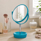 Blue plastic swivel table mirror on vanity with makeup brushes