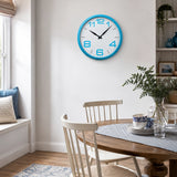 Blue plastic wall clock above dining table with plants and chairs