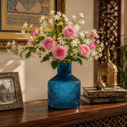 Blue textured glass vase filled with pink and white flowers on a wooden console table