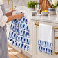 Blue and white fish-print cotton kitchen tea towels hanging on white shaker cabinet doors