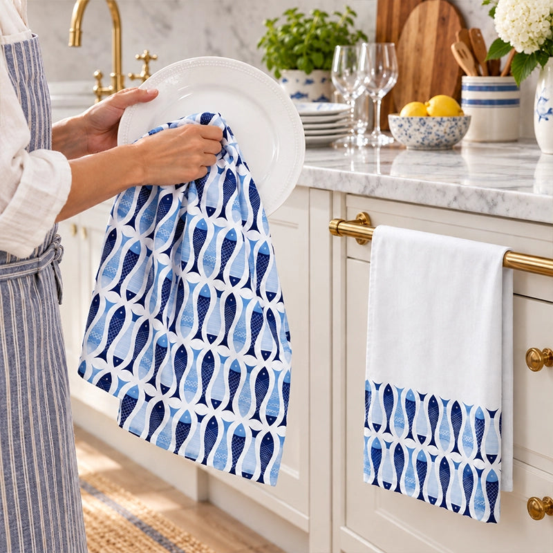 Blue and white fish-print cotton kitchen tea towels hanging on white shaker cabinet doors