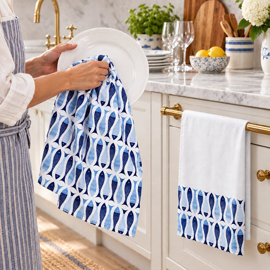 Blue and white fish-print cotton kitchen tea towels hanging on white shaker cabinet doors