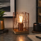 Brown metal table lamp with wire frame and exposed bulb on desk