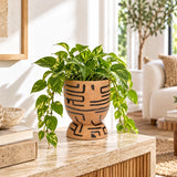 Decorative brown textured planter holding a green plant on a warm wooden indoor surface