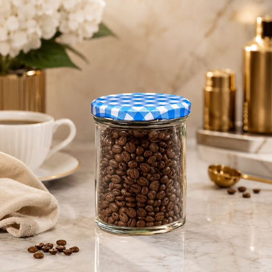 Clear glass storage jar with blue check lid filled with coffee beans on a kitchen worktop