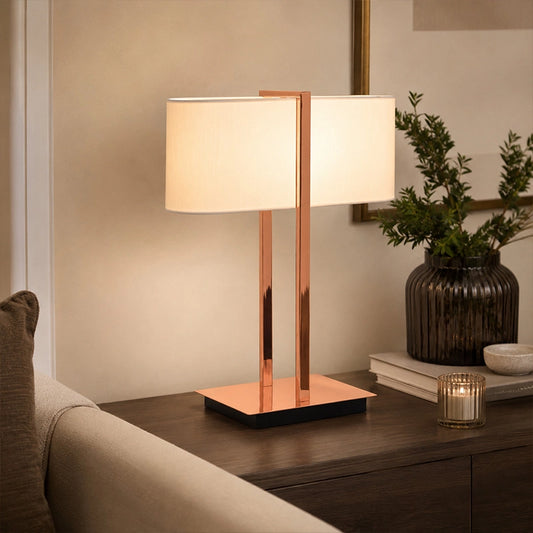 Copper finish table lamp with white shade on side table beside sofa
