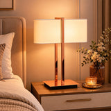Copper finish bedside table lamp with white shade and warm light