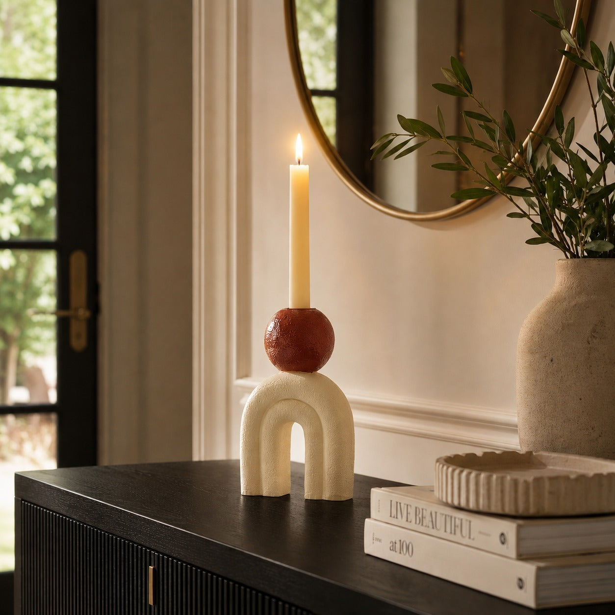 Cream decorative candle holder with arch design, brown sphere detail and tall taper candle