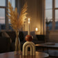 Cream arch-shaped candle holder with rounded brown detail and a tall lit taper candle